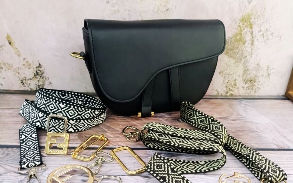 Herrajes para bolsos y marroquinería con bolso negro, correa estampada y piezas metálicas